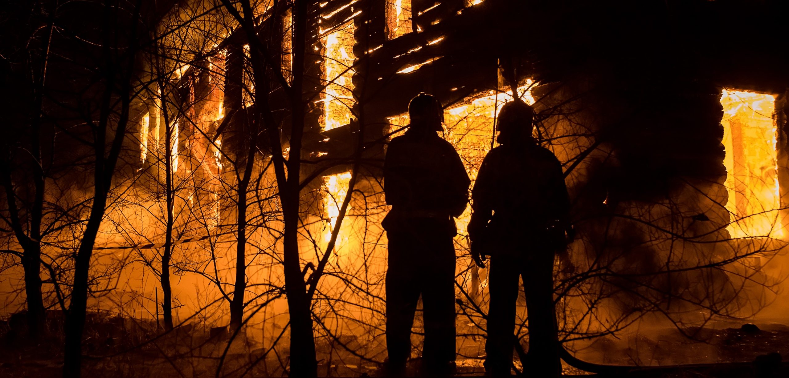 Silhouette of two people beside building on fire